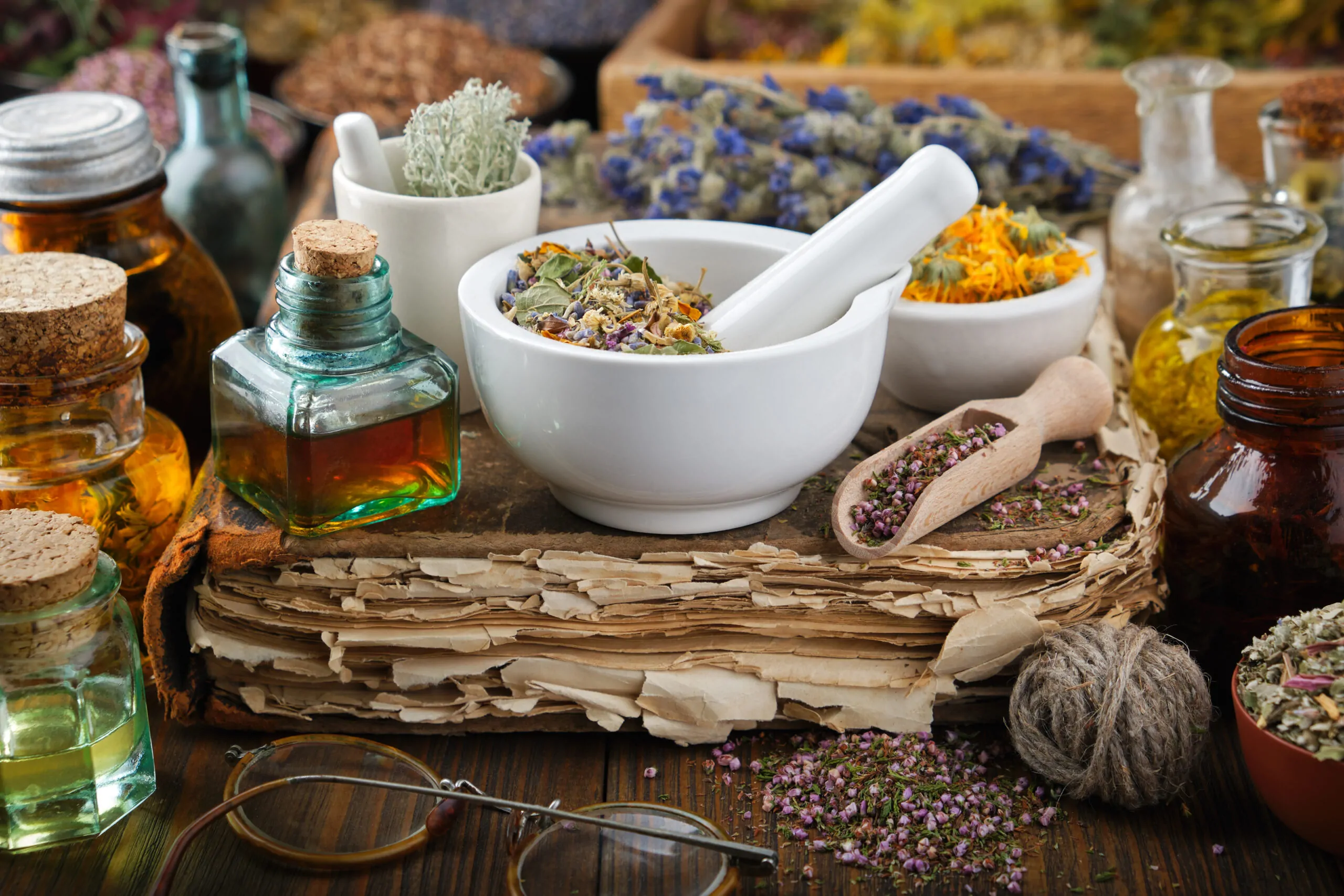 Bottles of healthy infusion or oil, mortars and bowls of medicinal herb, old book. Herbal medicine. Bottles of healthy infusion or oil, mortars and bowls of medicinal herb, old book. Herbal medicine.
